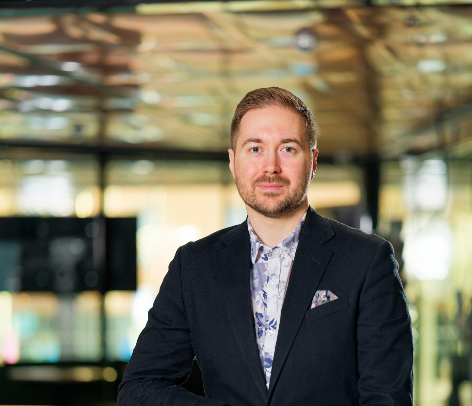 Lauri Lavanti istumassa tuolilla ikkunan edessä, katse kameraan, hymyillen. Hänellä on päällään valkoinen kauluspaita, jossa on sinisiä kukkakuvioita, sekä tumma pikkutakki. Kuvan otti Juha Jantunen.