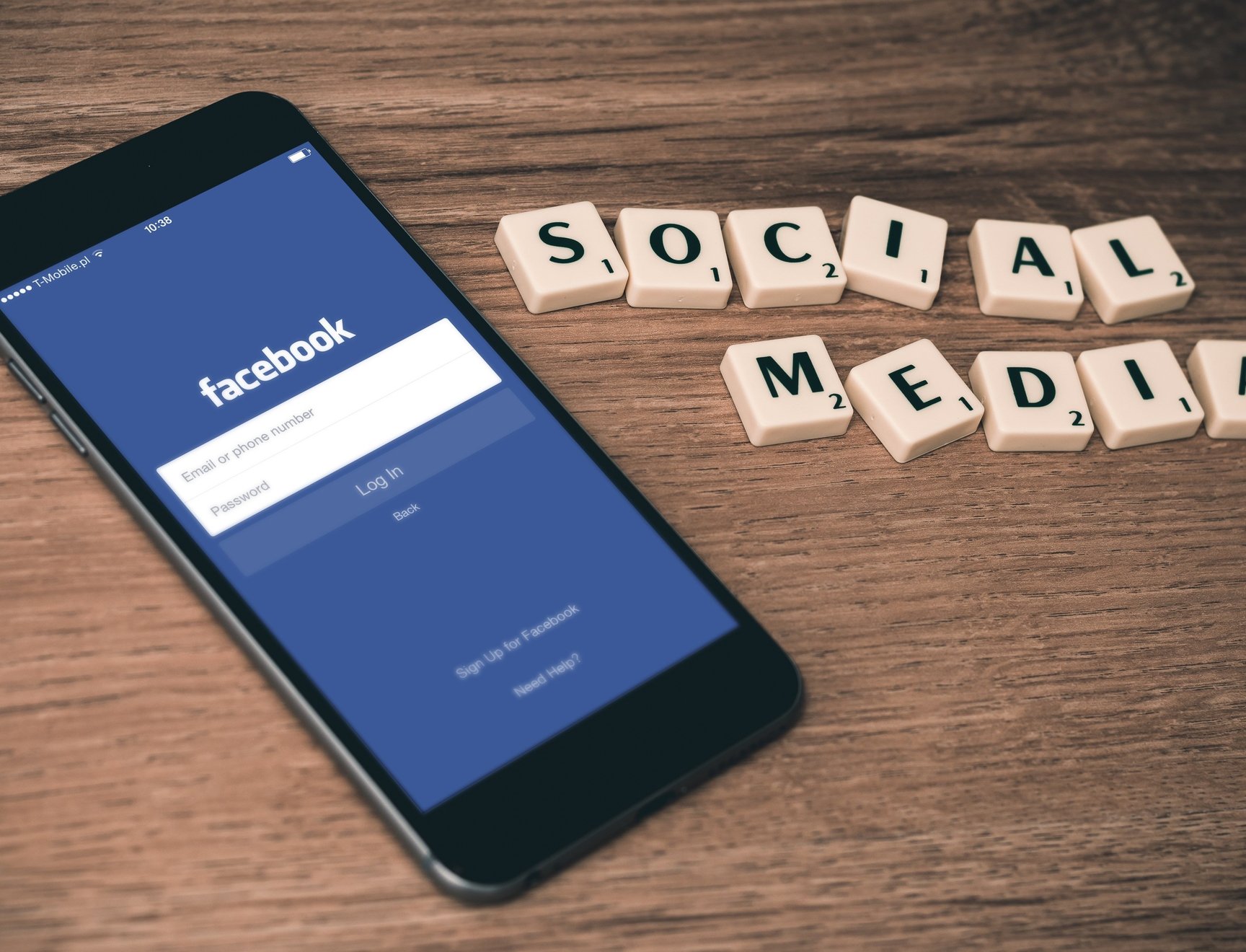 Puhelin, jossa on auki Facebookin sovellus odottamassa kirjautumistietoja sekä Scrabble-pelistä tutuilla nappuloilla tehty teksti "Social media"