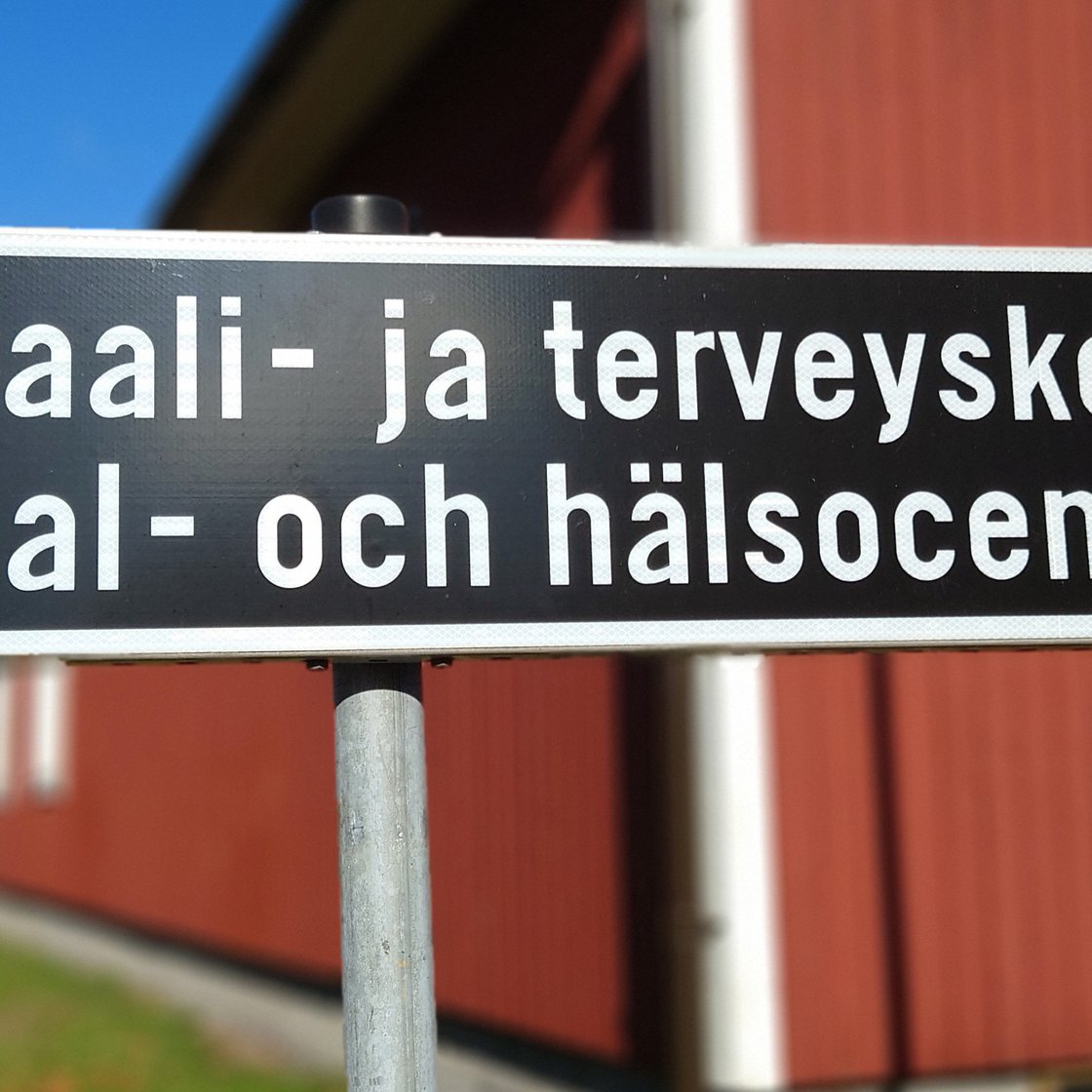 Kuva tiekyltistä, jossa lukee Sosiaali- ja terveyskeskus, sekä alla sama ruotsiksi, eli Social- och hälsocentral.