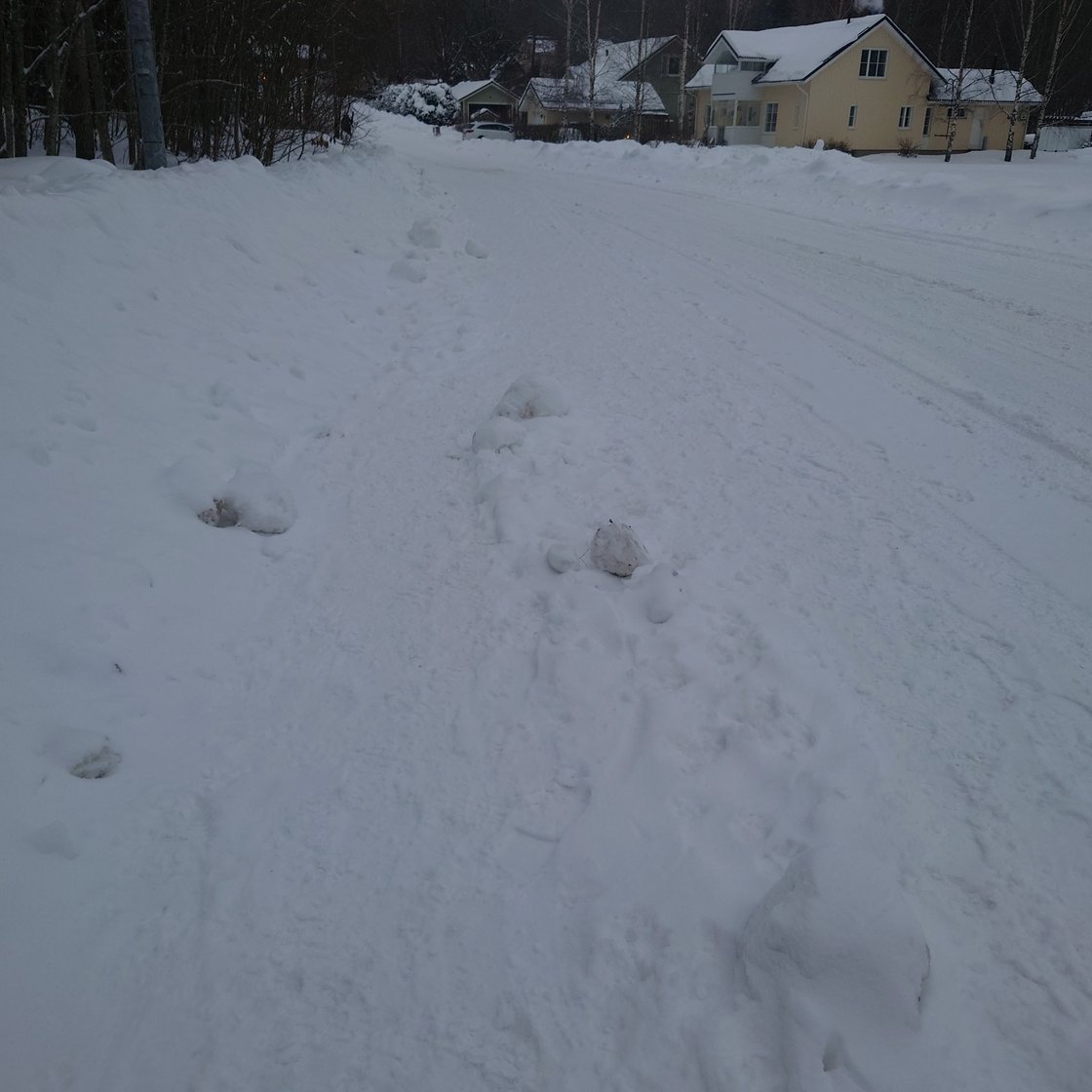 Kuva huonosti auratusta jalkakäytävästä, jonka vieressä on huolella aurattu autotie.